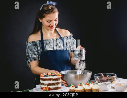 Buona confettiera vestita in vecchio stile femmina setacciando farina bianca alla ciotola Foto Stock