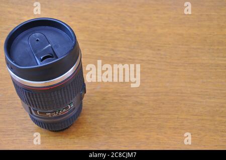 A forma di lente termica, imita l'obiettivo originale della fotocamera, con un coperchio, per acqua, birra o caffè, su sfondo di legno, Brasile, Sud America Foto Stock