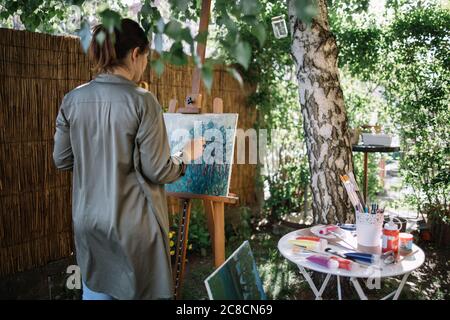 Pittura di artista femminile su una tela in studio esterno Foto Stock