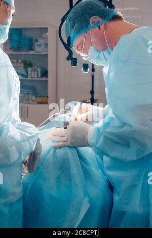 Team di chirurgia che fa chirurgia plastica sul naso in una sala chirurgica Foto Stock