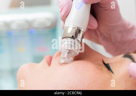 Salone di bellezza. Il cosmetologo effettua una procedura di peeling dell'acqua per il cliente. Primo piano di viso e dispositivo. Il concetto di cura professionale della pelle. Foto Stock