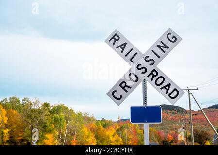 Cartello di attraversamento ferroviario in campagna in un giorno nuvoloso d'autunno. Gli alberi autunnali colouful sono visibili sullo sfondo. Spazio di copia. Foto Stock