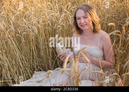 Ritratto di una donna caucasica incinta seduta in stile Rye, vintage. Foto Stock