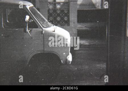 Fine anni '70 vintage nero e bianco stile di vita fotografia di un pulmino bianco in auto per la strada. Foto Stock