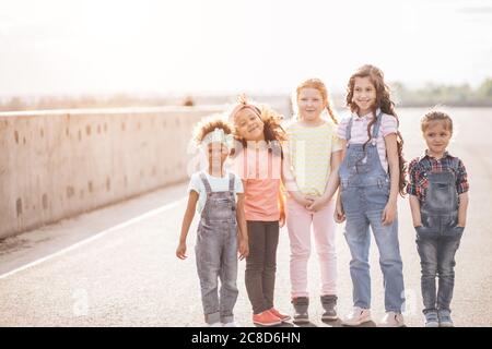 bella bambina in posa, guardando a fianco e sorridendo, il concetto di amicizia e comunicazione interculturale Foto Stock