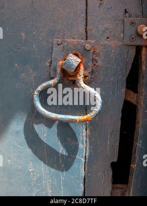 Primo piano della maniglia della porta sul vecchio sportello stabile Foto Stock