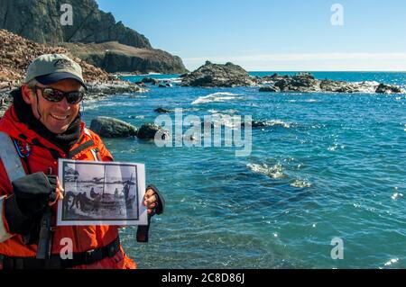 Il leader della spedizione Mike Messick sta tenendo in mano una foto storica di Point Wild, dove gli uomini della spedizione di Shackleton Endurance 1914 Foto Stock