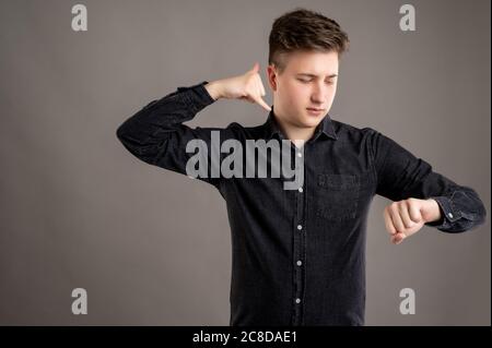 Ritratto di uomo elegante e di grande stile vestito con una camicia nera casual che mostra il gesto di chiamata o di contatto isolato su sfondo grigio con copia Foto Stock