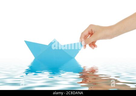 mano del ragazzo con barca di carta blu isolata su bianco Foto Stock