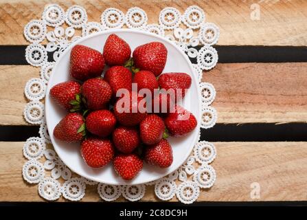 Fragole mature su un piatto su piastre di legno, vista dall'alto, spazio per il testo Foto Stock