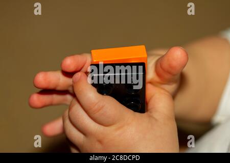 Immagine ravvicinata delle mani di un bambino mentre sta cercando di bloccare due mattoncini giocattolo. L'immagine è utile per dimostrare lo sviluppo del motore, la fine del motion Foto Stock