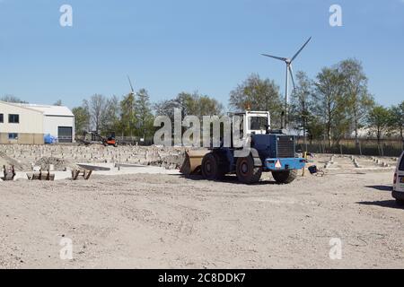 Pali di calcestruzzo prefabbricati quadrati in un luogo di costruzione. Condotto a suolo usando macchina di palo di calcestruzzo. In lontananza un moderno mulino a vento. Alkmaar. Olanda Foto Stock