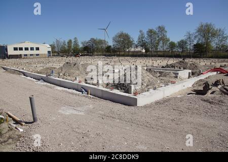 Pali di calcestruzzo prefabbricati quadrati in un luogo di costruzione. Condotto a suolo usando macchina di palo di calcestruzzo. In lontananza un moderno mulino a vento. Alkmaar. Olanda Foto Stock