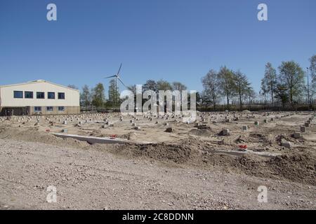 Pali di calcestruzzo prefabbricati quadrati in un luogo di costruzione. Condotto a suolo usando macchina di palo di calcestruzzo. In lontananza un moderno mulino a vento. Alkmaar. Olanda Foto Stock