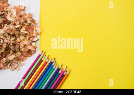 Matite e trucioli di colore su sfondo giallo brillante con copyspace per il testo. Ritorno a scuola, hobby o formazione concetto, fuoco selettivo Foto Stock