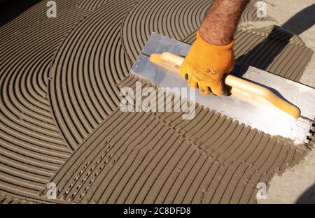 spalmare i pavimenti con colla con cazzuola intagliata Foto Stock