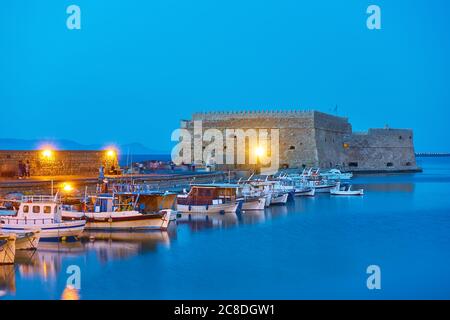 Barche da pesca vicino alla Fortezza di Koules a Heraklion al crepuscolo, isola di Creta, Grecia Foto Stock