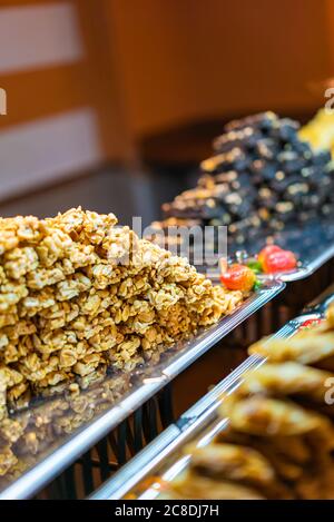 Tradizionale kozinaki del deserto orientale su un piatto di metallo a fuoco dolce. Bar di arachidi arrosto in un miele dolce o caramello. Dolci sani, utili e gustosi Foto Stock