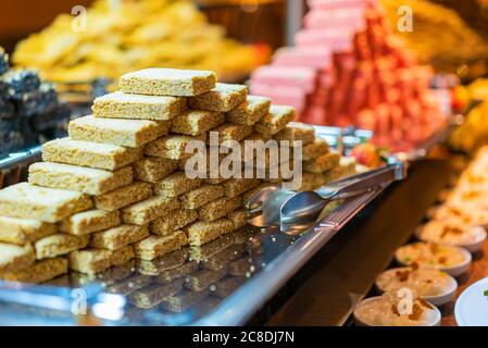 Tradizionale kozinaki del deserto orientale su un piatto di metallo a fuoco dolce. Barra di semi di sesamo arrostito in un miele dolce o caramello. sw sano, utile e gustoso Foto Stock