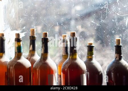 Bottiglie di vino o aceto fatti in casa con tappi sulla finestra Foto Stock