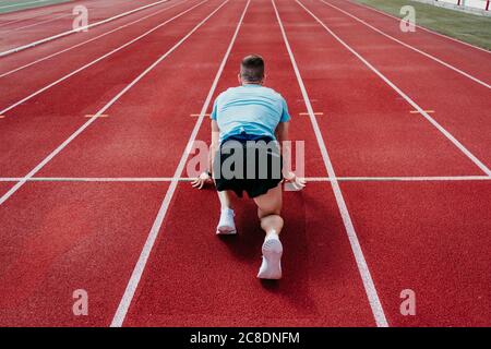 Atleta maschile in posizione di partenza sulla pista di tartan Foto Stock