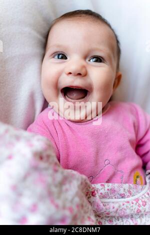 Ritratto di felice bambina in pyjama rosa su cui giace letto Foto Stock