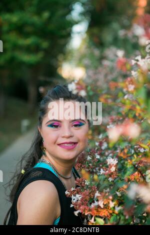 Adolescente ragazza con sindrome di Down indossando 80's colorful make-up e. vestiti guardando la macchina fotografica Foto Stock