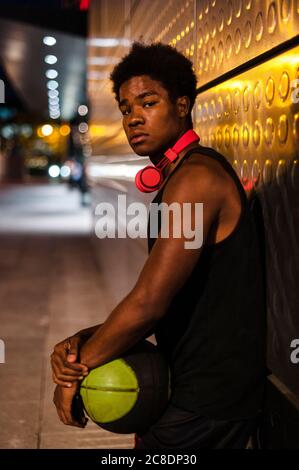 Ritratto di un giovane che tiene il basket di notte la città Foto Stock