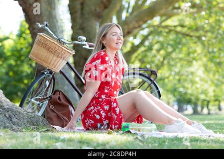 Donna premurosa seduta al parco pubblico Foto Stock