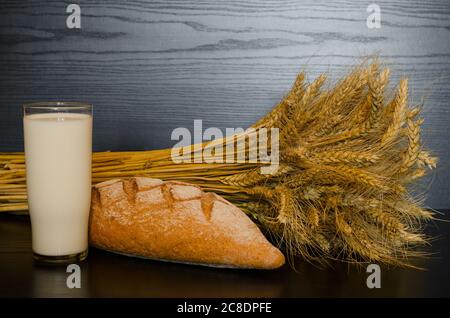 Un bicchiere di latte, pane integrale e un ovone su fondo scuro Foto Stock