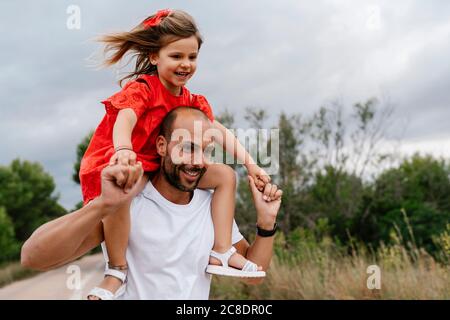 Uomo felice che porta la figlia sulle spalle in campagna Foto Stock