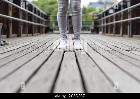 Primo piano di gambe donna in piedi sul ponte in città Foto Stock