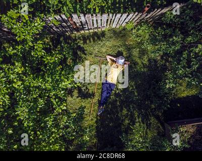 Vista aerea della donna mid adult con le mani dietro la testa riposando su terra erbosa in cortile Foto Stock