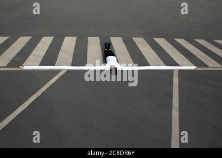 Donna con mani lunghe artificiali sdraiata sulla traversata di zebra Foto Stock