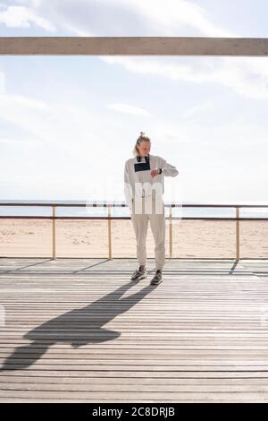 Giovane donna atletica che controlla il tempo sul jetty Foto Stock