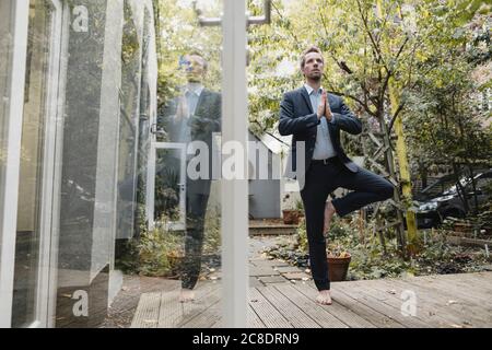 Uomo d'affari che pratica yoga in cortile Foto Stock