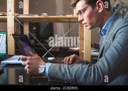 Uomo d affari con computer portatile alla scrivania in ufficio Foto Stock