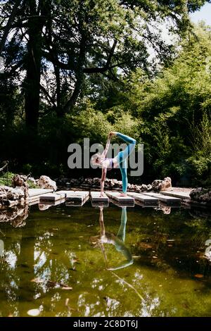 Donna consapevole della salute che fa yoga posa al parco pubblico Foto Stock