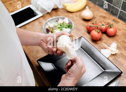 Uomo maturo in cucina, peeling cipolle Foto Stock