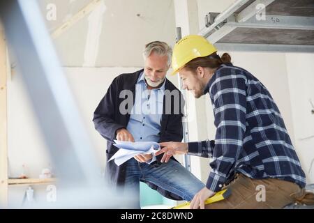 Architetto e lavoratore che discute di progetto edilizio in un cantiere Foto Stock