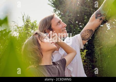 Padre che mostra qualcosa al figlio scherma gli occhi in cortile durante giorno di sole Foto Stock