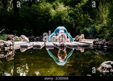 Donna che fa esercizio stretching al parco pubblico Foto Stock