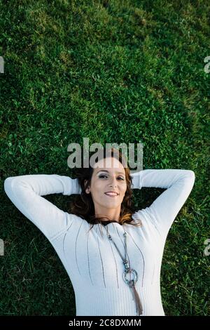 Felice donna mid adulta sdraiata sull'erba al parco Foto Stock