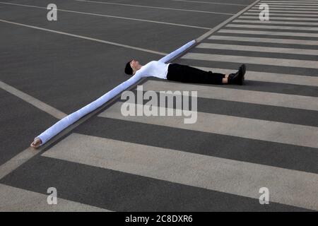 Donna con lunghe mani artificiali sdraiata sulla traversata di zebra Foto Stock