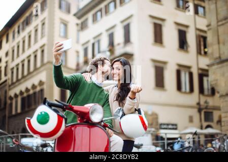 Uomo romantico che prende selfie mentre bacia donna a Firenze città, Italia Foto Stock