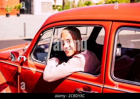 Ritratto di ragazzo felice adolescente seduto in auto d'epoca guardando fuori dalla finestra Foto Stock