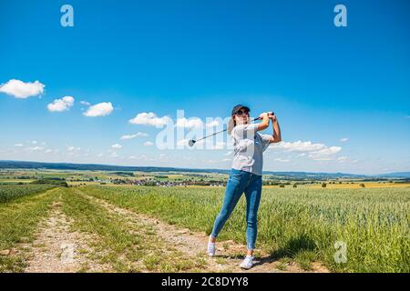 Giovane donna che gioca a golf in campagna Foto Stock