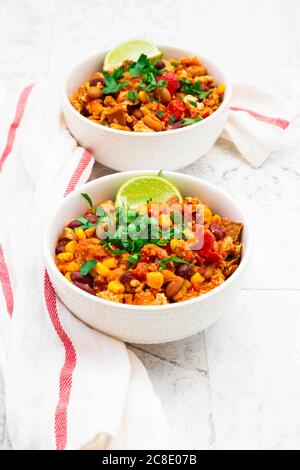 Due ciotole di peperoncino vegetariano con tofu, mais, rene e fagioli di pinto, coriandolo e lime Foto Stock