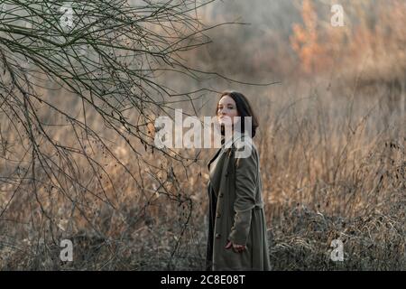 Bella donna matura in piedi da pianta morta a foresta Foto Stock