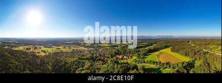 Germania, Baviera, Eurasburg, panorama aereo del sole che splende su villaggio di campagna ai piedi delle colline alpine Foto Stock